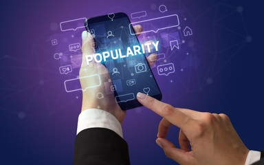 Female hand typing on smartphone with POPULARITY inscription, social media concept