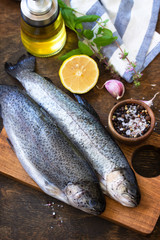 Fresh raw trout fish and pickle ingredients on a wooden table. Cooking grilled fish preparation.