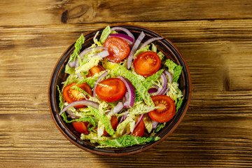 Healthy salad with savoy cabbage, cherry tomato, red onion and olive oil on wooden table. Top view