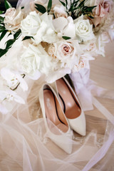 beautiful wedding composition of white shoes and veil with bridal bouquet, close view  