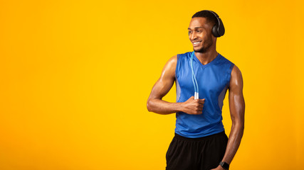 Black sportsman with jumping rope listening to music