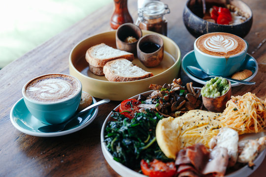 Morning breakfast on a table, waffles with cream, berries, coffee, cappuccino, bowl, omlet with vegetables, bread with butter, avocado cream, vegan food, healthy food, meal.