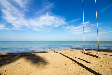 lonely swing on a dreamlike beach in front of a heavenly turquoise sea
