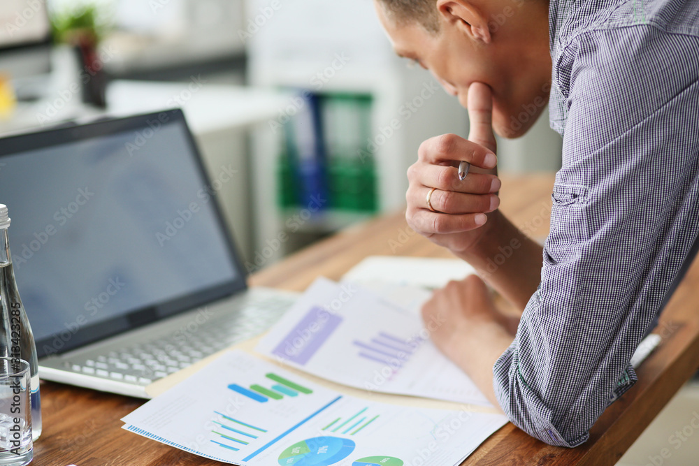 Fototapete side view of experienced businessman looking at financial data with graphics and charts while work o