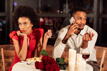 Bored Girl Having Dinner With Boyfriend Sitting In Restaurant