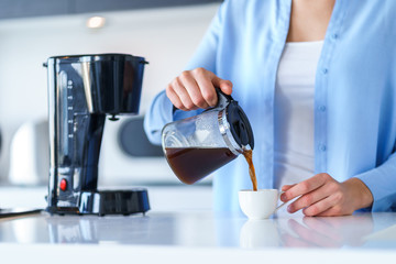 Woman using coffee maker for making and brewing coffee at home. Coffee blender and household kitchen appliances for makes hot drinks