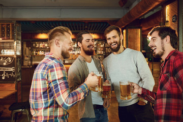 Group of happy friends clinking glasses with beer at a sports bar.