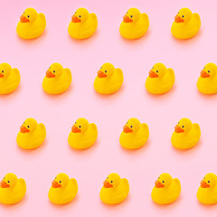 Trendy still life pattern made with Yellow plastic rubber ducks on pastel pink background. Minimal background with isometric view