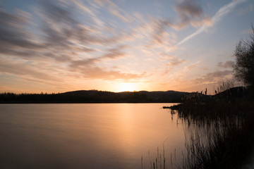 Sonnenaufgang über einem See mit hügeln im Hintergrund