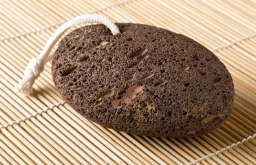 Black lava pumice stone spa or bath utensil used for peeling or callused skin removal on bamboo mat