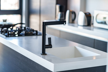 Black kitchen faucet with a white sink in a stylish luxury modern kitchen