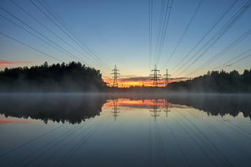 Fototapeta na wymiar Power lines are reflected in the water at sunset