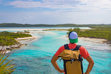 Männlicher Tourist mit Rucksack schaut auf das tropische Meer in der Karibik, Long Island Bahamas