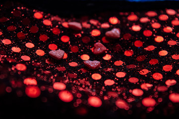 Valentines day background.  Red little hearts on the red sparkles. Bokeh background. Blurred lights. Love and romantic concept. 