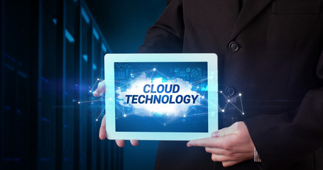 Young business person working on tablet and shows the inscription: CLOUD TECHNOLOGY