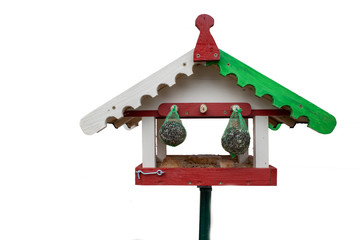 a bird house painted green and red stands against a white background