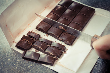 girl's hands, cut a chocolate bar with a knife