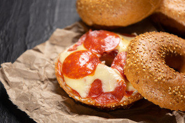 Sesame bagels with pepperoni and cheese on dark background