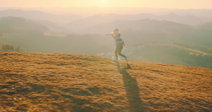 Happy traveler boy playing with airplane toy on sunny day in park. 4K slow motion video. Child runs on top of mountain at sunset. Journey to the Edge of the Universe