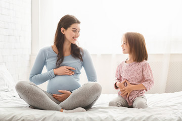 Obraz premium Expecting woman telling little daughter about pregnancy
