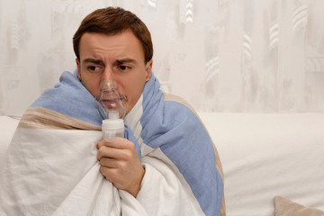 Colds and flu. The guy wrapped in a blanket sits on the bed