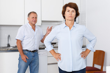 Obraz premium Unhappy mature female standing after qurrel with husband at home