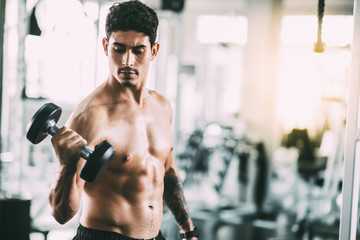 Man bodybuilder lifting dumbbell weights. Man training in a gym Fitness.workout, exercises and...