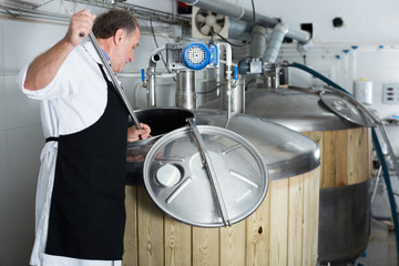 Brewer is controls the brewing process near reservoir with beer