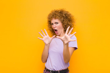 young afro woman feeling terrified, backing off and screaming in horror and panic, reacting to a...
