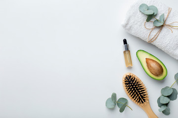 Bamboo accessories, avocado and essential oil on white