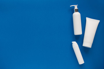 White empty cosmetic tubes on blue background. Concept night and winter skin care. With copy space. Flat lay. Top view.