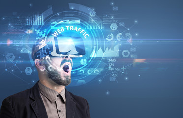 Businessman looking through Virtual Reality glasses with WEB TRAFFIC inscription, innovative technology concept