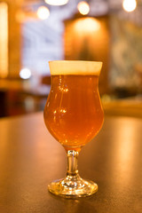 Glass of light beer on a dark pub.