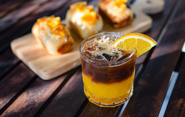 Coffee with orange juice and orange bread on a wooden table