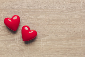 Stock photo of red plastic hearts on a wooden background with space for text
