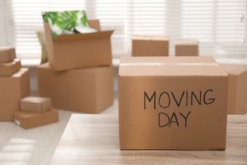 Cardboard box with words MOVING DAY on wooden table