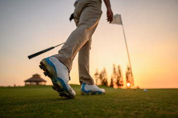 lifestyle, golf, activity, outdoor, sport, golfer concept. Side view of a golfer walking on a sand...