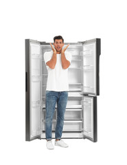Fototapeta na wymiar Man near open empty refrigerator on white background