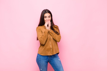 young pretty woman happy and excited, surprised and amazed covering mouth with hands, giggling with...
