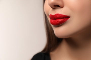 Beautiful woman with red lipstick on light background, closeup. Space for text