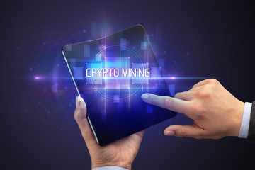 Businessman holding a foldable smartphone with CRYPTO MINING inscription, new technology concept