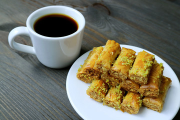 Plate of Pistachio Nuts Baklava Pastries with a Cup of Turkish Coffee Served on Wooden table