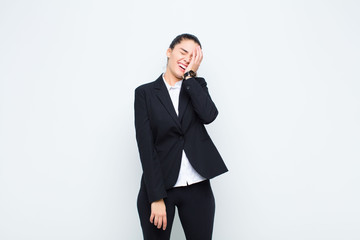 young pretty woman laughing and slapping forehead like saying d‚Äôoh! I forgot or that was a...