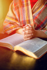 Beautiful woman praying having the Bible opened in front of he