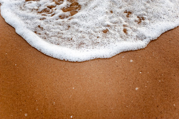 Sea, beach, sand, wave, summer, background concept. White waves on a sandy beach in the summer on sunset. Background sea concept.