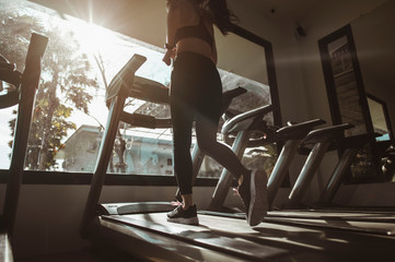Fototapeta na wymiar fitness, workout, gym exercise, lifestyle and healthy concept. Women walking on the treadmill in the gym for good health and strength at sunset.