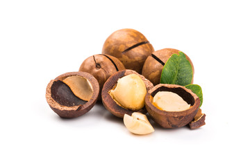 Macadamia nut with pieces and green leaves isolated on a white background