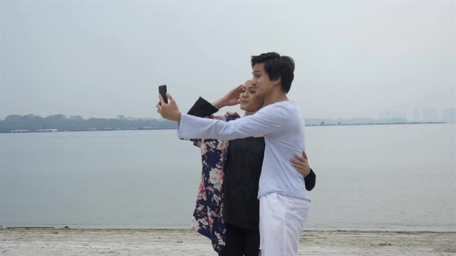 A Romantic Malaysian Couple Taking A Photo At The Beach 
