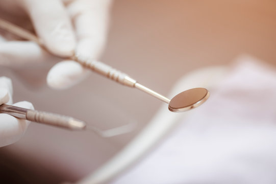 The dentist's hand holds the tooth checker and a mirror for checking and caring for the dentist's tools and equipment..