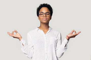 Attractive african woman doing meditation pose isolated on grey background
